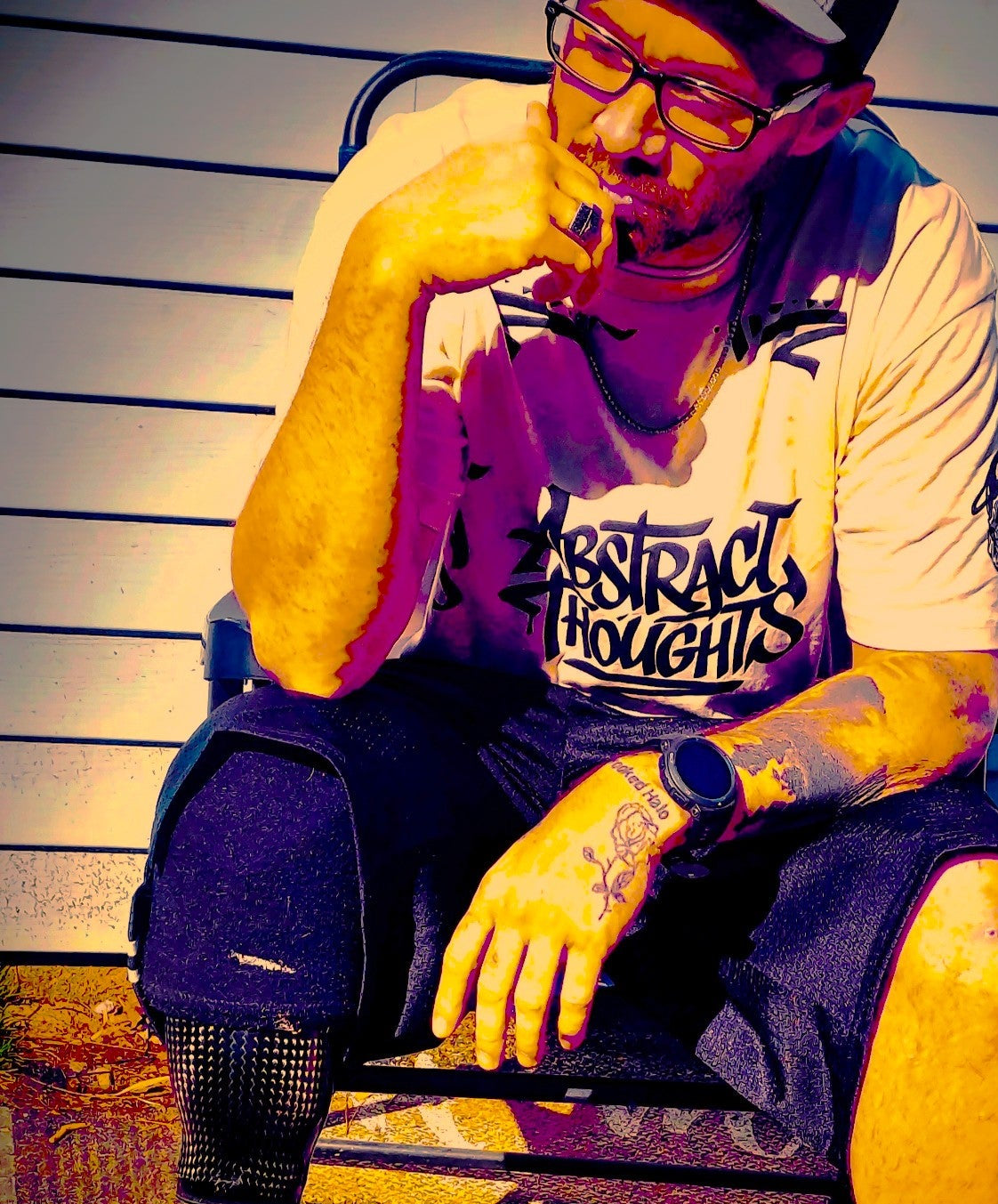 Person with tattoos sitting on a chair against a striped wall. Crooked Halo. Abstract Thoughts.